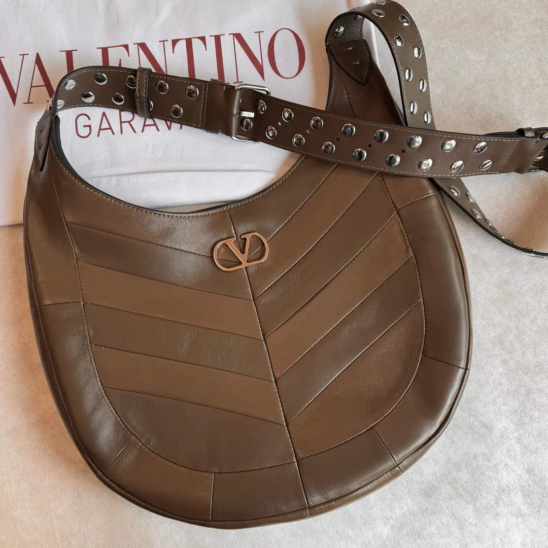 Large. Valentino.GARAVANI HOBOHO HOBO Handbags are designed in a synthesizing system., It's made of bright and dumb sheep leather. V Font, And used to treat it with a copy of the old brass. VLOGO SIGNATURE Metal Details. This bag is equipped with a regressable shoulder belt., But the shoulder can slash.. Regulating leather shoulder belts, Pride, nail. Large size: 35 X 27 X 4 centimetres Model: 2026